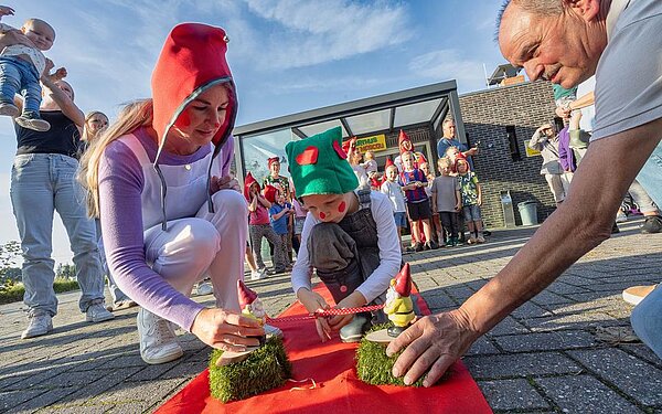 twee kaboutertjes die een lint vasthouden dat door een jongen wordt doorgeknipt