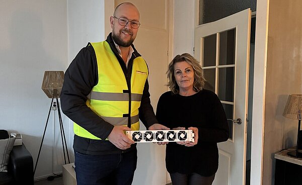 Een man en een vrouw die een radiatorventilator vasthouden