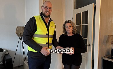 Een man en een vrouw die een radiatorventilator vasthouden